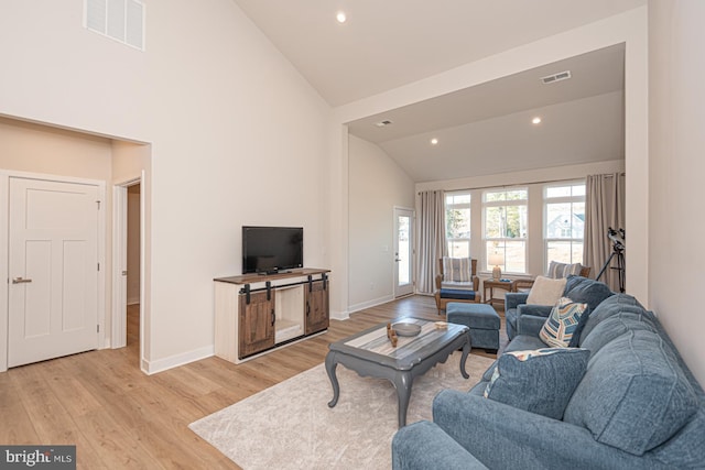 living area with high vaulted ceiling, visible vents, light wood-style flooring, and baseboards