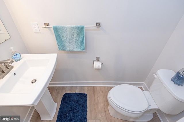 bathroom with toilet, baseboards, a sink, and wood finished floors