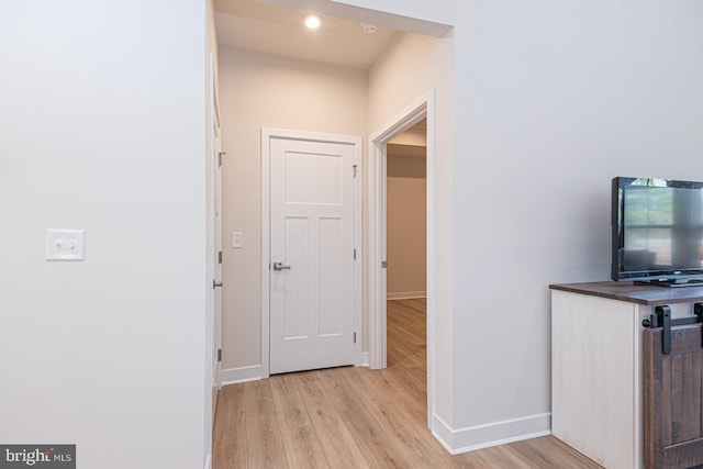 corridor featuring light wood-type flooring and baseboards