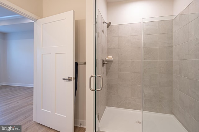 full bathroom featuring a stall shower, baseboards, and wood finished floors