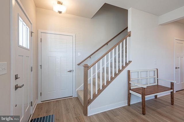 foyer entrance featuring stairs, visible vents, baseboards, and wood finished floors