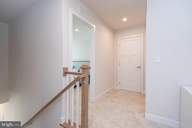 corridor featuring baseboards, visible vents, light carpet, and an upstairs landing