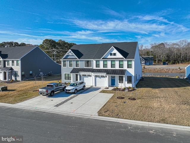 multi unit property with metal roof, a garage, concrete driveway, a standing seam roof, and a front yard