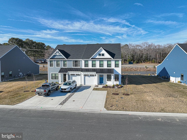 townhome / multi-family property with metal roof, an attached garage, driveway, a standing seam roof, and a front yard