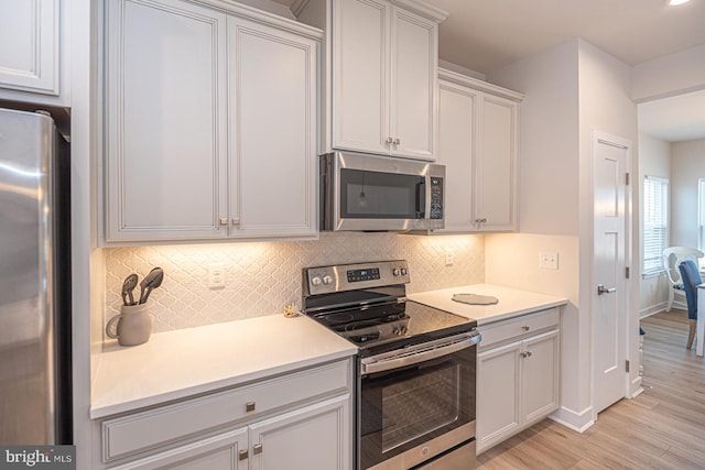 kitchen featuring tasteful backsplash, baseboards, light wood-style flooring, stainless steel appliances, and light countertops