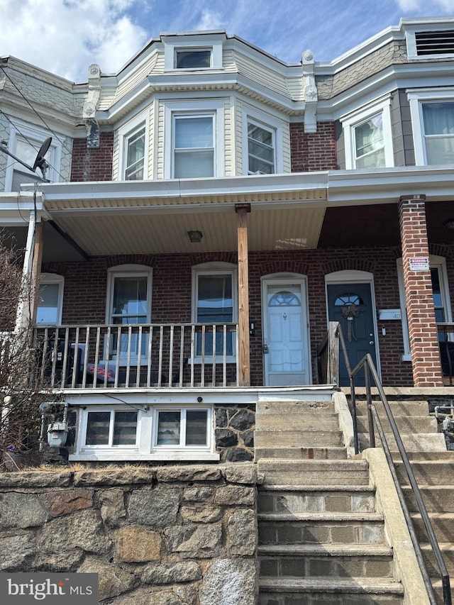 view of front of house with a porch and brick siding