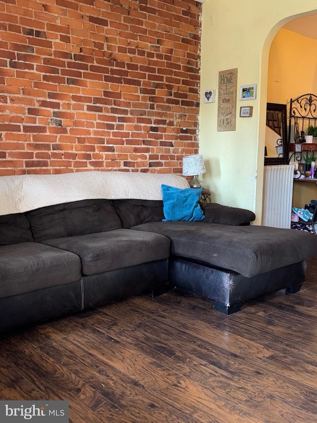 living room featuring arched walkways, radiator, and wood finished floors