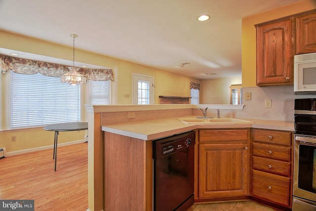 kitchen with brown cabinetry, black dishwasher, a sink, and white microwave