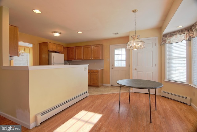 kitchen featuring visible vents, a baseboard heating unit, freestanding refrigerator, brown cabinetry, and light wood-style floors