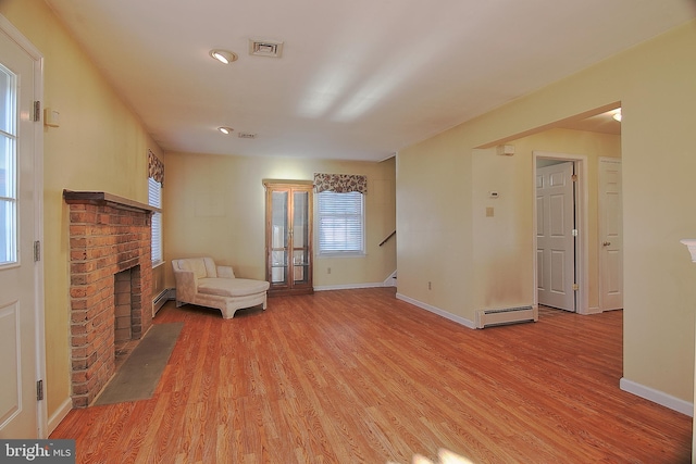 unfurnished room with a baseboard radiator, a fireplace, visible vents, baseboards, and light wood-style floors