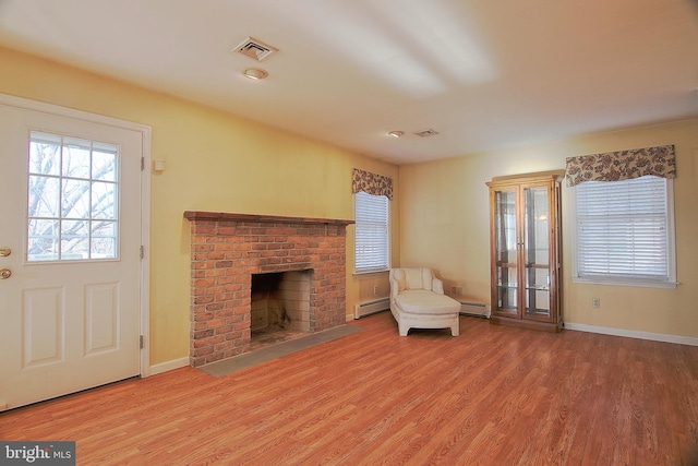 unfurnished living room featuring a brick fireplace, baseboards, baseboard heating, and wood finished floors