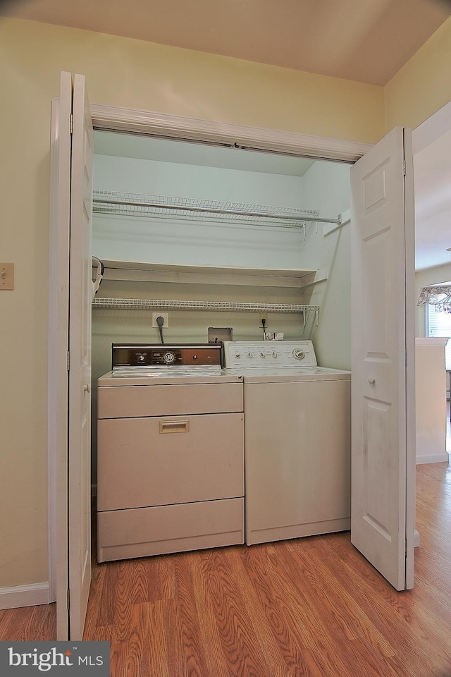 laundry area featuring laundry area, baseboards, light wood-style floors, and independent washer and dryer