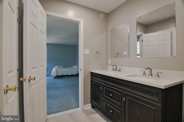 bathroom with baseboards, a sink, ensuite bath, and double vanity