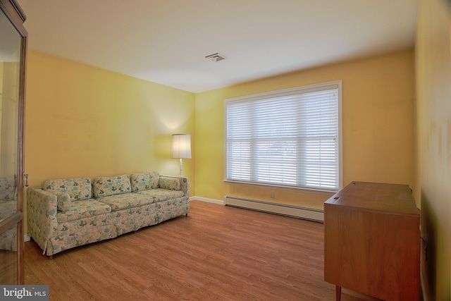 living room with visible vents, a baseboard heating unit, and wood finished floors