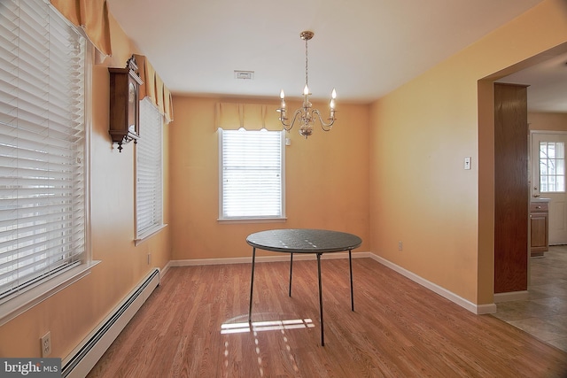 unfurnished dining area with a notable chandelier, a baseboard radiator, visible vents, wood finished floors, and baseboards