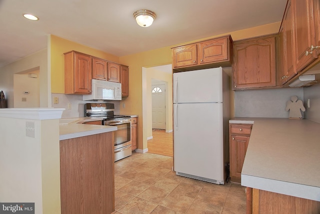 kitchen with light countertops, white appliances, brown cabinetry, and baseboards