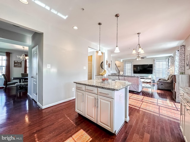 kitchen featuring light stone counters, plenty of natural light, a center island, and dark wood finished floors