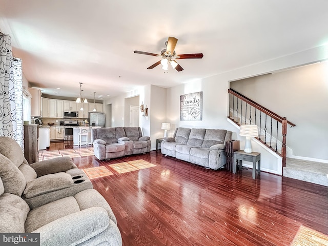 living area with stairs, ceiling fan, wood finished floors, and baseboards