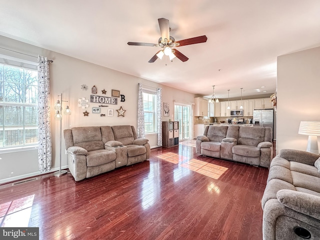 living room featuring baseboards, visible vents, ceiling fan, and dark wood-type flooring