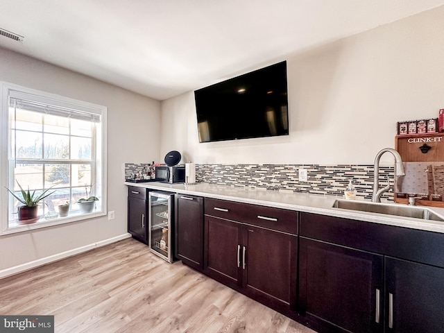 bar featuring visible vents, wine cooler, a sink, light wood-type flooring, and backsplash