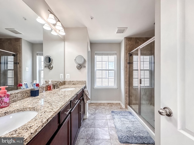 full bath with visible vents, a sink, a shower stall, and double vanity