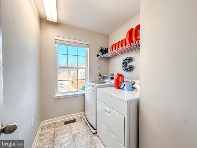 laundry area with laundry area, washing machine and clothes dryer, visible vents, and baseboards