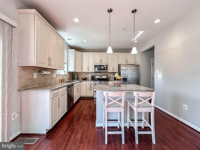 kitchen with stainless steel appliances, backsplash, a sink, and dark wood finished floors