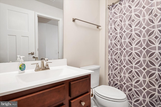 bathroom featuring curtained shower, toilet, and vanity