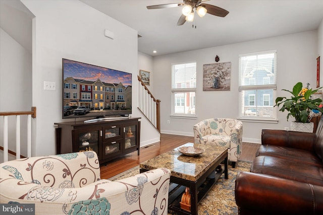 living area with visible vents, baseboards, stairway, wood finished floors, and a ceiling fan