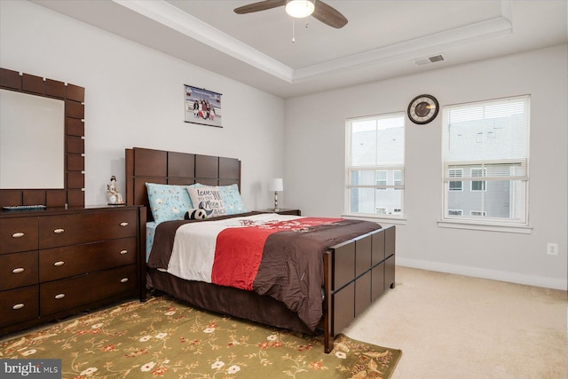 bedroom with a tray ceiling, carpet flooring, baseboards, and visible vents