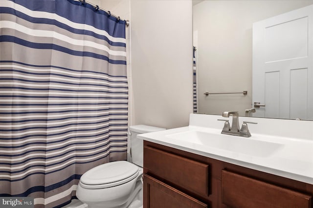 bathroom featuring toilet, vanity, and a shower with curtain