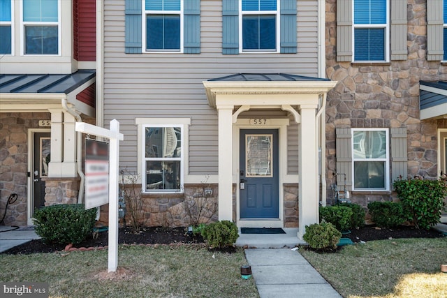 doorway to property featuring metal roof, stone siding, and a standing seam roof