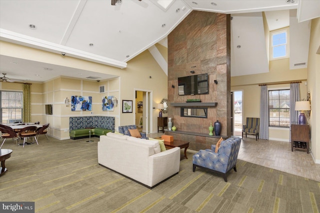 living room with visible vents, baseboards, a ceiling fan, and a towering ceiling