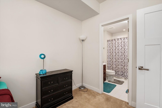 bedroom with baseboards, carpet floors, visible vents, and ensuite bathroom