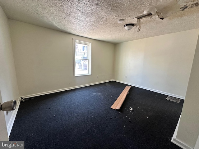 spare room featuring visible vents, a textured ceiling, and baseboards