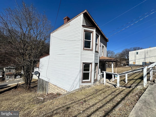 view of side of home featuring a chimney and fence