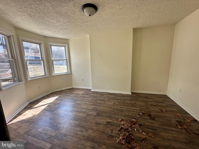 unfurnished room with a textured ceiling, baseboards, and dark wood-type flooring