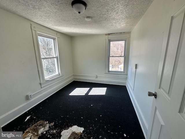 unfurnished room featuring a textured ceiling and baseboards