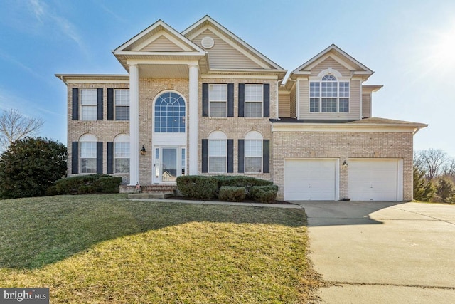 neoclassical / greek revival house featuring driveway, a garage, a front yard, and brick siding