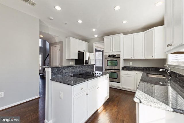 kitchen featuring stainless steel appliances, dark stone counters, a sink, and dark wood-style floors