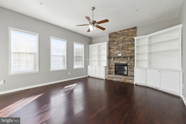 unfurnished living room with dark wood-style floors, ceiling fan, a fireplace, and baseboards