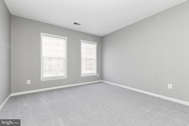 spare room featuring baseboards, visible vents, and carpet flooring