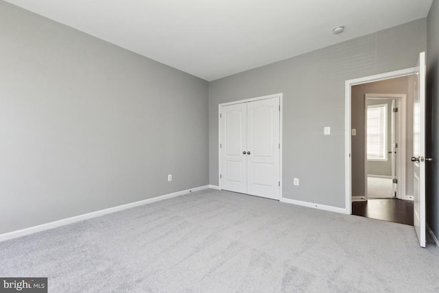 unfurnished bedroom with a closet, carpet flooring, and baseboards