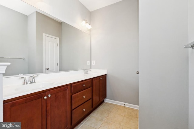 bathroom with double vanity, tile patterned flooring, baseboards, and a sink