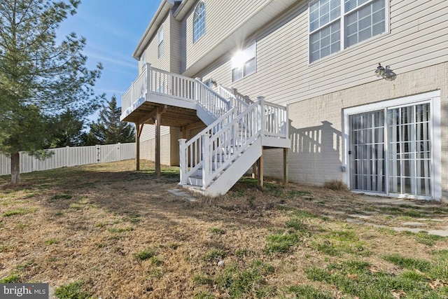 exterior space featuring brick siding, fence, stairway, and a wooden deck