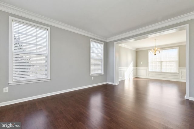 spare room featuring crown molding, a chandelier, wood finished floors, and wainscoting