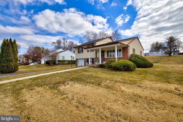 split foyer home featuring an attached garage, covered porch, brick siding, driveway, and a front yard