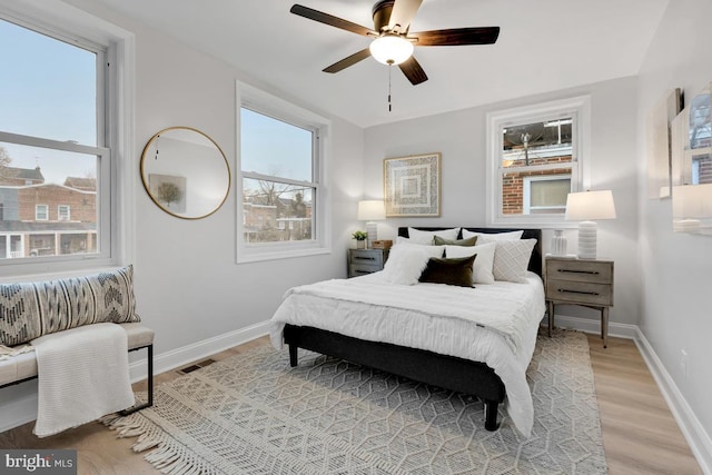 bedroom with light wood-style floors, baseboards, visible vents, and a ceiling fan