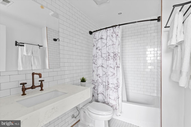 full bathroom featuring tile walls, visible vents, toilet, shower / tub combo, and a sink