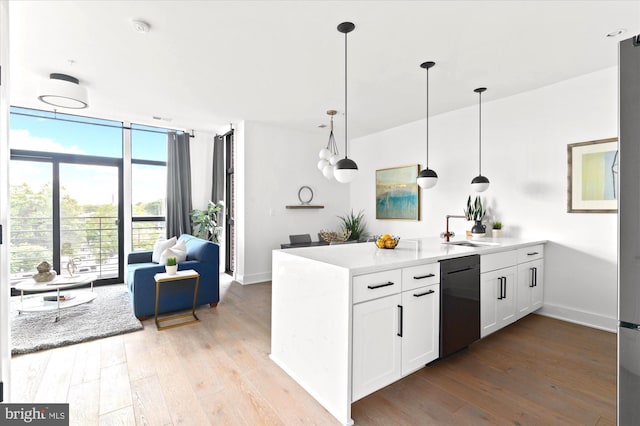 kitchen with light wood finished floors, black dishwasher, expansive windows, and a sink